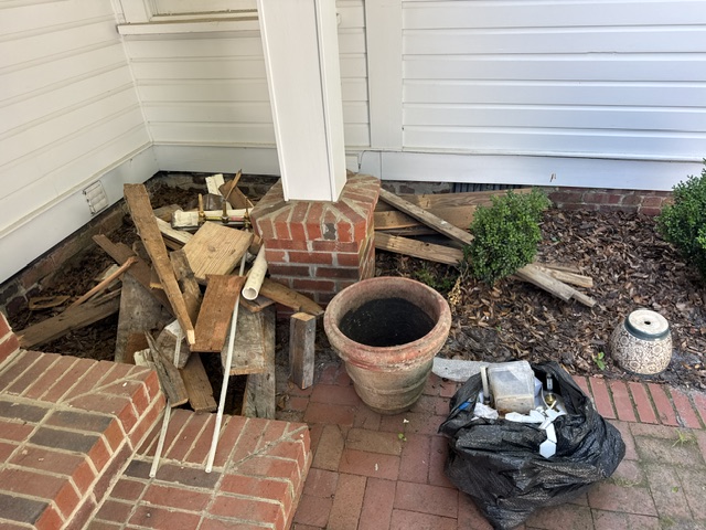 Before: old lumber, removed sink basin, and cabinet stacked outside Pinehurst Village renovation home