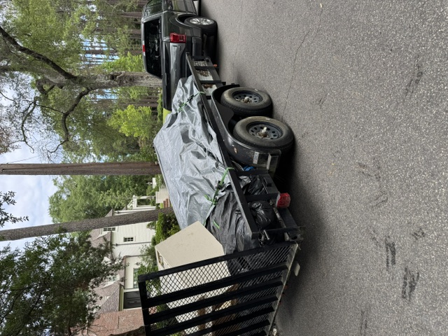 Renovation debris trailer loaded and tarped on tree-lined street in Village of Pinehurst NC
