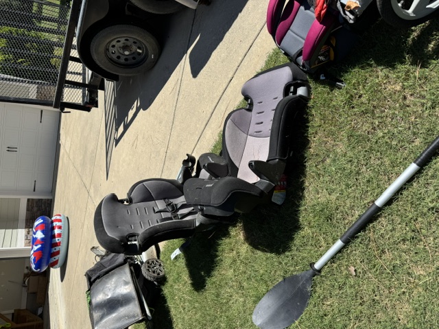 Junk hauled out of garage and staged on driveway in Pinehurst NC — car seat, kayak paddle, pool float
