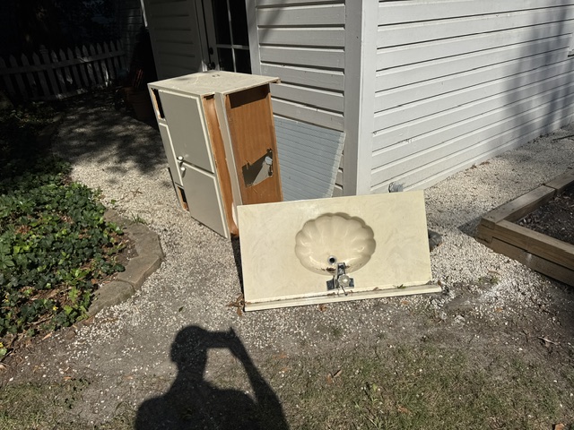 Before: old refrigerator cabinet and removed countertop sink staged outside during Pinehurst renovation